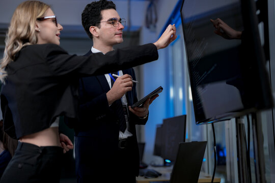 A quantum computing scientist explains a complex algorithm to a colleague, pointing to the code that will run on a quantum processor to solve a problem previously thought impossible.