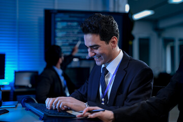 Two software developers smile with satisfaction during a pair programming session, as one points to a successfully executed block of code after solving a complex programming problem.