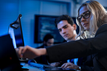 Two software developers smile with satisfaction during a pair programming session, as one points to...