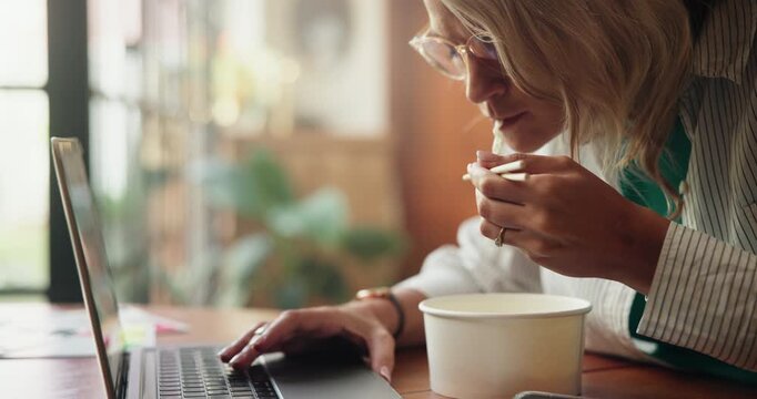 Chinese food, laptop and remote work with woman in home for hunger, lunch break or research. Chopsticks, computer and freelance employee eating ramen noodles at counter in apartment for planning