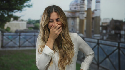 Obraz premium Young blonde woman touches hair on roman terrace; joy happiness freedom adventure.