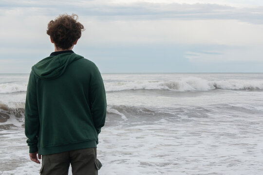 Person standing on the shore looking at the ocean waves.