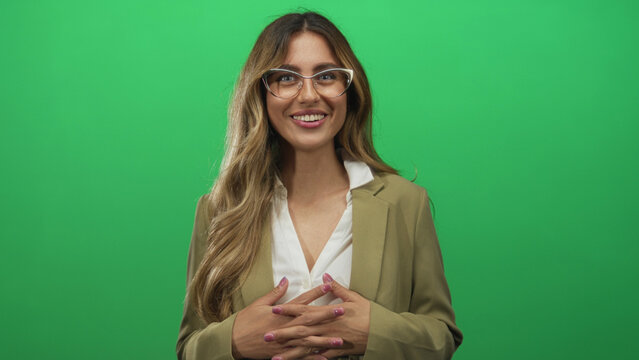 Woman clasps hands in front of green screen studio; confidence engagement professionalism communication.
