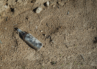 Discarded Glass Bottle on Sandy Ground