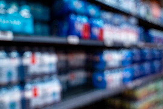 Blurred view of bottled beverages on market shelf.