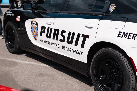 black Dodge Charger highway patrol. Front left A-pillar of police car with search light. Police cruiser with spotlight lamp. NY, USA - May 25 2025