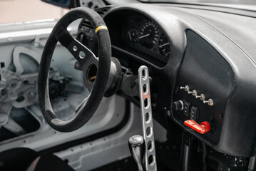 Race car interior, cockpit filled with bright sunlight. Close-up image of steering wheel and dashboard in drift car. © andrbk
