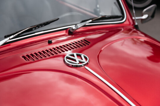 Emblem near the windshield of old VW Beetle. Shiny chrome emblem on the front trunk of red 1960s Volkswagen bug. Kyiv, Ukraine - May 10 2025
