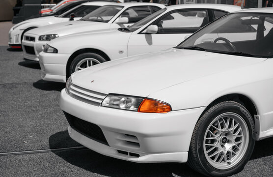 Four Nissan Skyline GT-Rs of different generations. Horizontal image of 1990s-2000s Nissan cars on a sunny day in parking lot. Osaka, Japan - June 11 2025