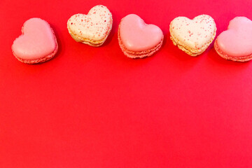 Sweet heart shaped macaroons on red background. Top view, copy space. Valentine Day concept