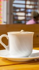 white coffee in a cup on a brown table