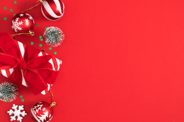 Festive Christmas composition with red and white balls, gift box and decor on a bright red...