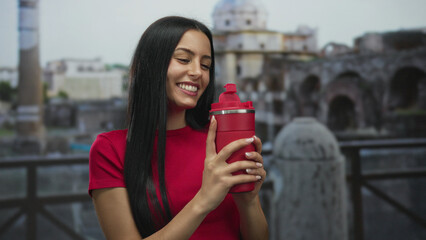 Woman smiling with a red bottle at roman ruins, showcasing vibrant ambiance and historic...