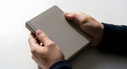 Hands holding a simple gray notebook, ready for writing or planning.