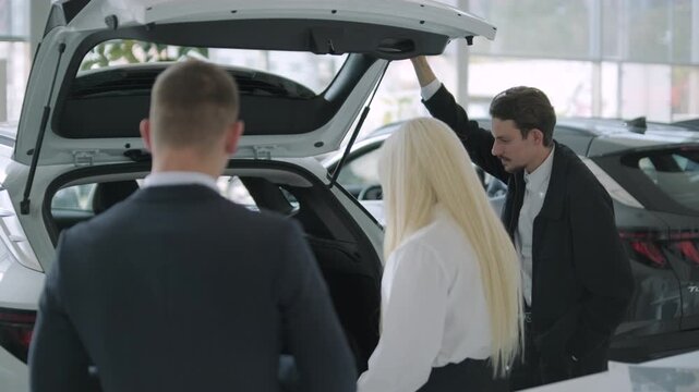 Car buyers exploring vehicles with sales agent assistance at dealership
