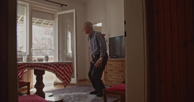 An elderly man focuses on his health, performing gentle daily exercises and stretches for his knees and back in his comfortable home environment.