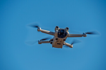 Eine Kameradrohne fliegt vor einem wolkenlosen blauen Himmel