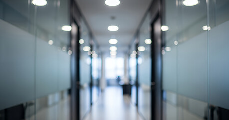 Reflections shimmer along the glass walls while bright natural light fills the blurred hallway, presenting a serene and modern office environment in soft focus.