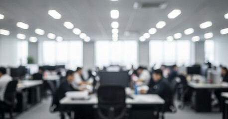 Modern office activity unfolds in a blurred view where employees concentrate at workstations beneath evenly spaced ceiling lights and natural light from tall windows.