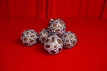 Large Christmas tree balls decorated with snake skin patterns lie on a red satin cloth. Creative...