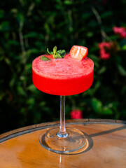 Strawberry daiquiri cocktail on a wooden barrel outdoors