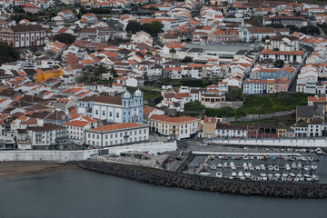 Aerial view of Angra do Heroísmo on Terceira Island, showcasing the town’s colorful rooftops, coastline, and lush volcanic landscape in the Azores, Portugal
