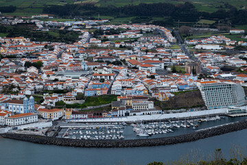 Obraz premium Aerial view of Angra do Heroísmo on Terceira Island, showcasing the town’s colorful rooftops, coastline, and lush volcanic landscape in the Azores, Portugal