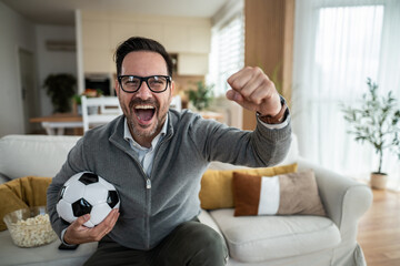 Excited man celebrating soccer victory watching tv at home © Migma_Agency