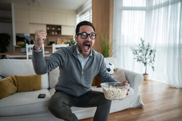 Excited man celebrating a goal watching a soccer match