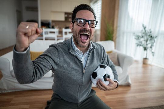 Excited soccer fan celebrating victory at home watching game
