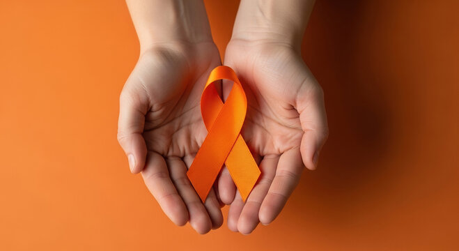 Human hands gently hold orange awareness ribbon on monochrome background, symbolizing multiple sclerosis and other conditions