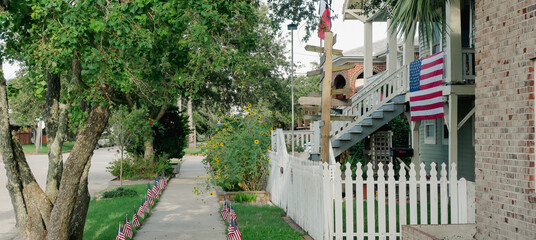 Panorama view directional signpost next to white picket fence front yard house features porch...