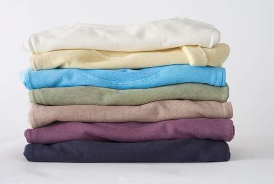 Stack of folded colorful baby clothes newborn apparel on white background