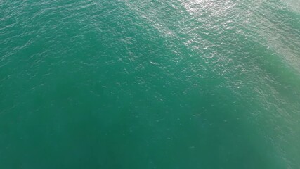 Aerial drone view of calm turquoise sea surface, gentle ocean water texture, peaceful natural waves, tranquil marine background, relaxing coastal environment, smooth seaside motion footage