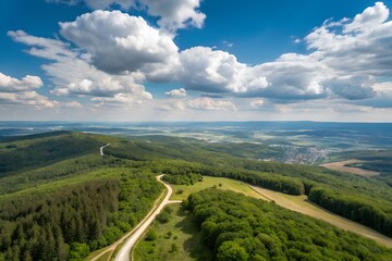 Aerial view of a winding road through lush green forest