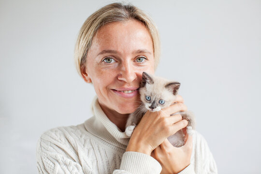 Portrait of middel aged woman with tiny cat kitten looking at camera at home - Powered by Adobe