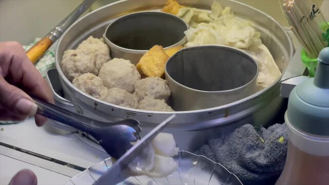 Video vendor preparing bakso (meatball) and tofu.