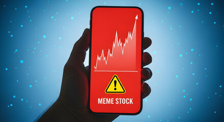 Hand holding smartphone displaying a meme stock warning with a rising stock chart against a blue background with bokeh lights indicating investment risk and market volatility in the digital age