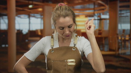 Woman in apron thinking inside cozy restaurant, blonde hair and caucasian features create a thoughtful atmosphere of inquiry in indoor coffee setting.