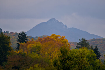 Obraz premium Mountain Peak Rises Above Vivid Autumn Forest Colors