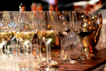 Elegant scene of wine being poured into glasses aligned in a row, showcasing the rich colors and graceful flow of the liquid, set against a dark, warm background, ideal sophisticated dining settings