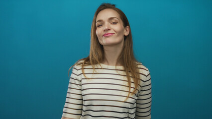 Obraz premium Young woman with slight smile pointing finger to temple in blue studio; creative idea thinking innovation.