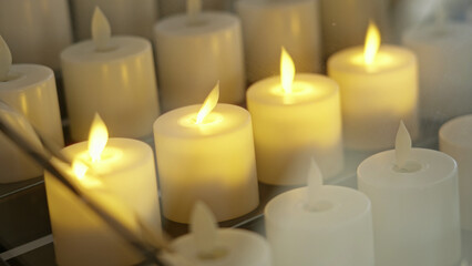 Glowing automated candles in church setting reflection symbolizes spirituality indoors peaceful ambiance representing faith donation