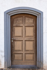 Vintage wooden doorway with charm, oldfashioned wooden archway set against textured white wall