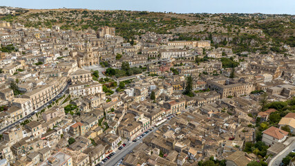 Obraz premium Aerial view of the historic center of Modica, in the province of Ragusa, Sicily, Italy. At the center is the Cathedral of San Giorgio, example of baroque architecture. It's a sunny summer day.