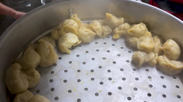 freshly steamed momos arranged in metal steamer tray ready to serve