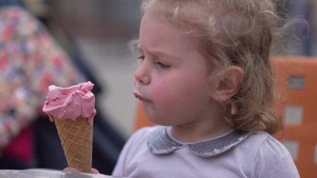 Little girl's delight a springtime indulgence with a pink ice cream cone in the Park on a Sunny Afternoon