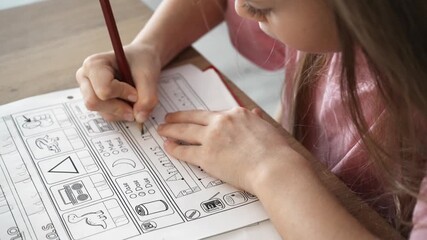 Young Caucasian girl engaged in handwriting exercises at home desk, Adolescent white female diligently practicing handwriting skills on wooden table in focused study environment
