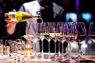 Waiter pouring wine into wineglass. Waiter work. Sommelier pours alcoholic drink
