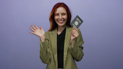 Redhead woman smiling and waving while holding italian passport against isolated purple background...